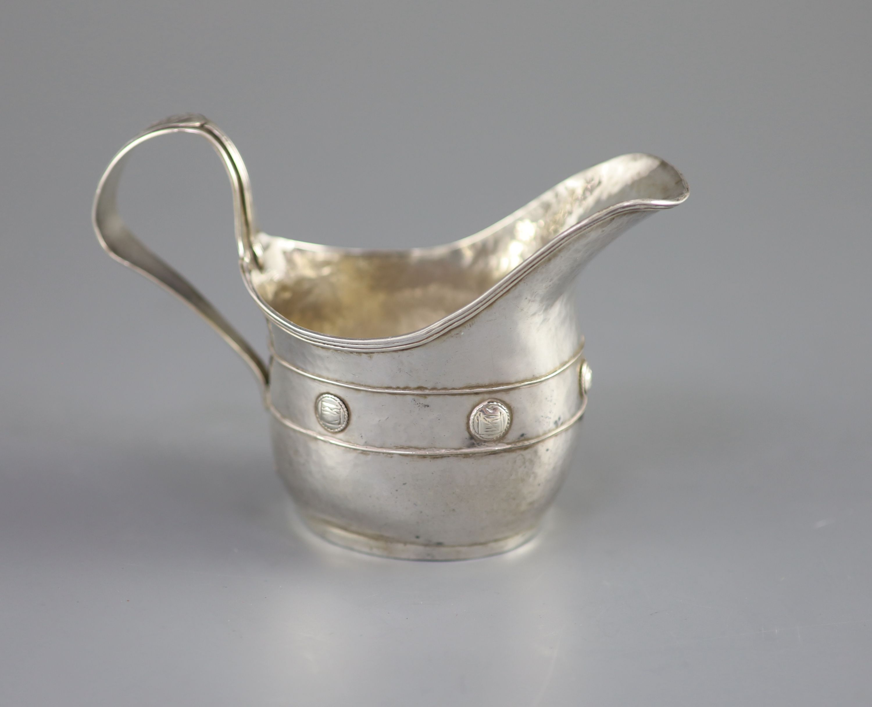 An Edwardian Arts & Crafts planished silver cream jug by John Gatecliff